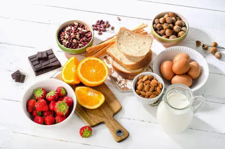 A variety of whole foods, including bread, oranges, strawberries, nuts, milk, and eggs.