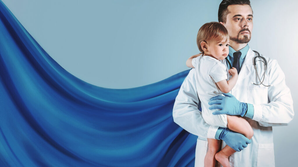 Confident doctor with superhero cape is holding little boy on his hands.
