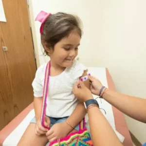 Young girl gets adhesive medical strip on her arm from medical professional